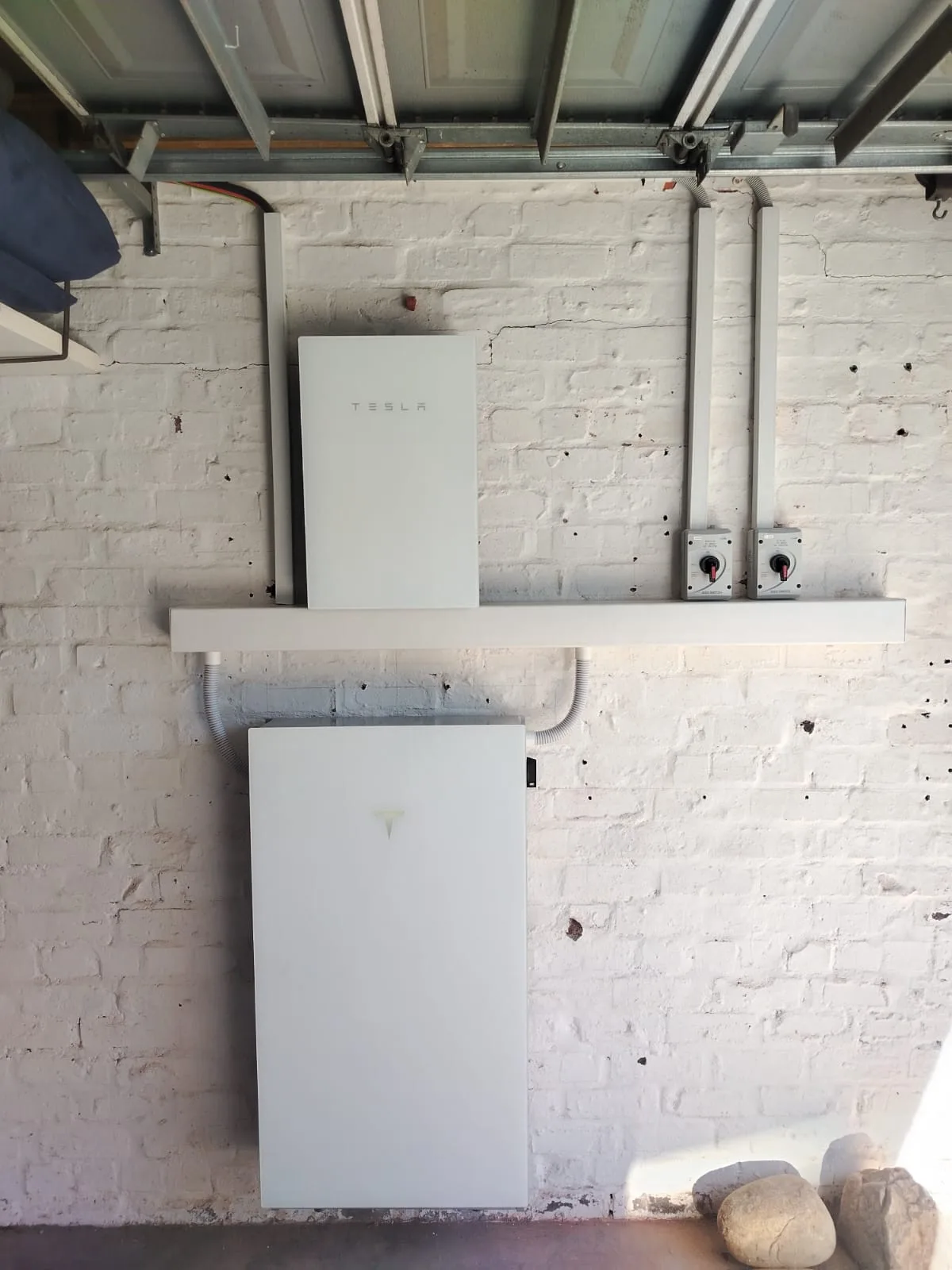 Tesla Powerwall 3 and Tesla Backup Gateway installed on a white brick garage wall by MLT Power in Cape Town